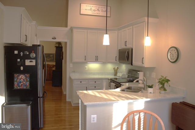 kitchen featuring white cabinetry, a peninsula, stainless steel appliances, and a sink