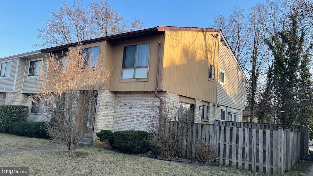 view of home's exterior with fence and brick siding