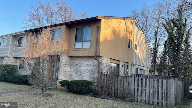 view of home's exterior with fence and brick siding