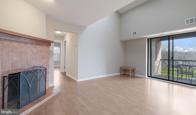 unfurnished living room with visible vents, baseboards, wood finished floors, and a tile fireplace