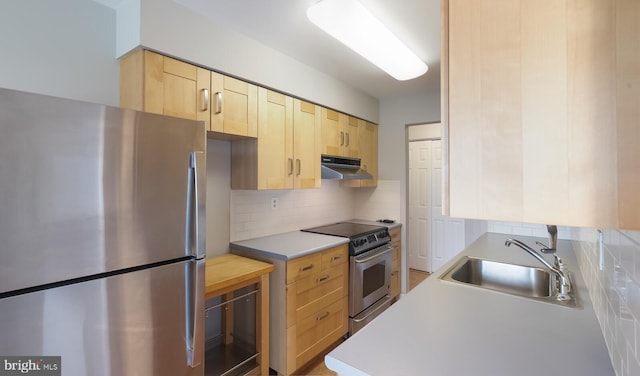 kitchen with light brown cabinets, a sink, stainless steel appliances, under cabinet range hood, and backsplash