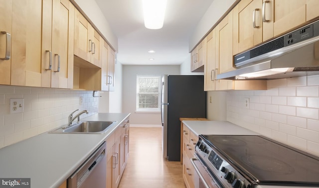 kitchen featuring tasteful backsplash, light brown cabinets, under cabinet range hood, appliances with stainless steel finishes, and a sink