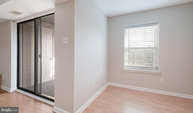 empty room featuring visible vents, baseboards, and wood finished floors