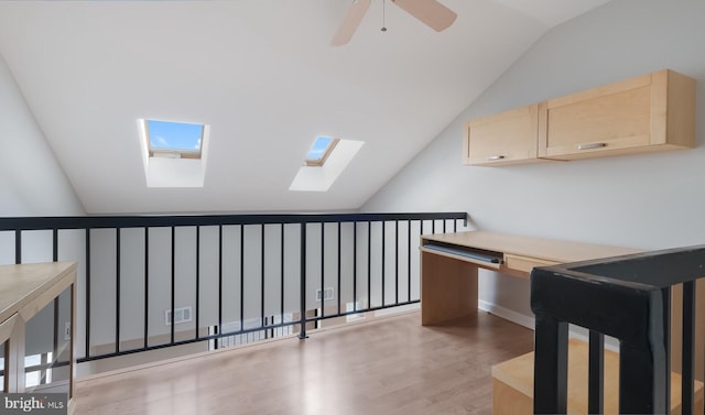 hallway featuring vaulted ceiling with skylight and wood finished floors