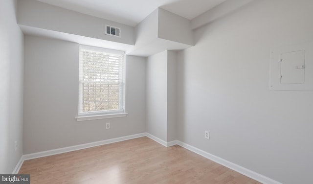 spare room featuring electric panel, visible vents, baseboards, and light wood-style flooring