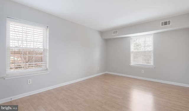 unfurnished room featuring visible vents, baseboards, and wood finished floors