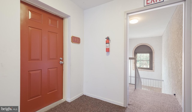 hallway featuring baseboards, carpet floors, and arched walkways