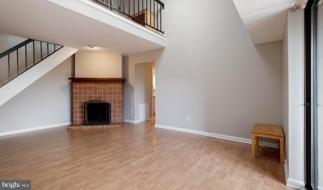 unfurnished living room with baseboards, wood finished floors, and stairs