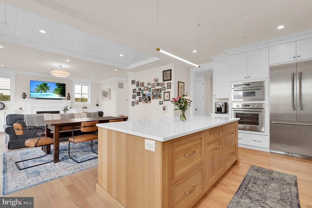 kitchen featuring open floor plan, light countertops, light wood-type flooring, stainless steel appliances, and a center island