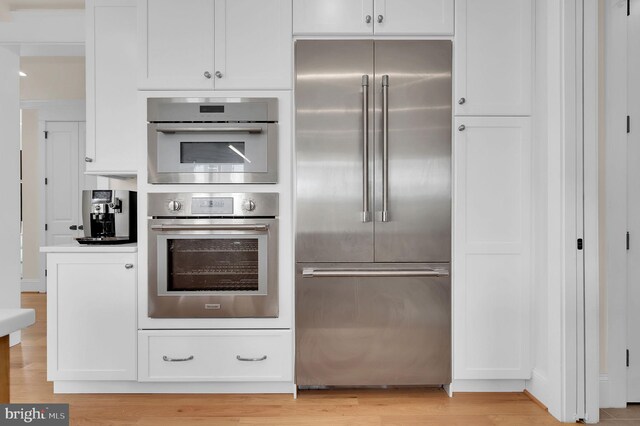 kitchen with light wood finished floors, white cabinets, and stainless steel appliances