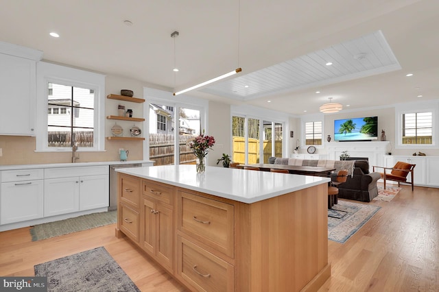 kitchen featuring light countertops, a center island, light wood finished floors, and open shelves