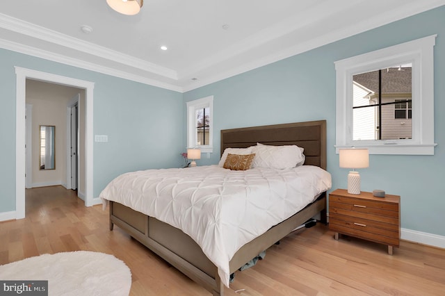 bedroom with baseboards, multiple windows, crown molding, and light wood finished floors