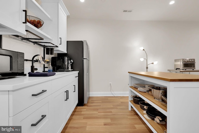 kitchen with white cabinets, visible vents, light wood finished floors, wood counters, and open shelves