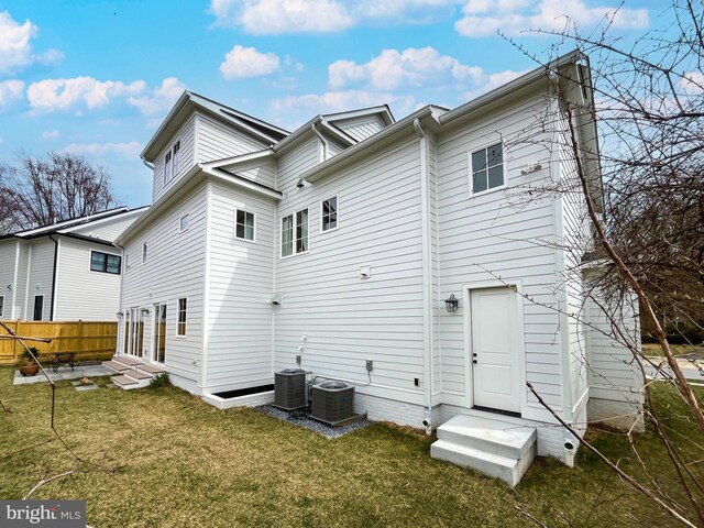 rear view of property featuring a lawn, fence, central air condition unit, and entry steps