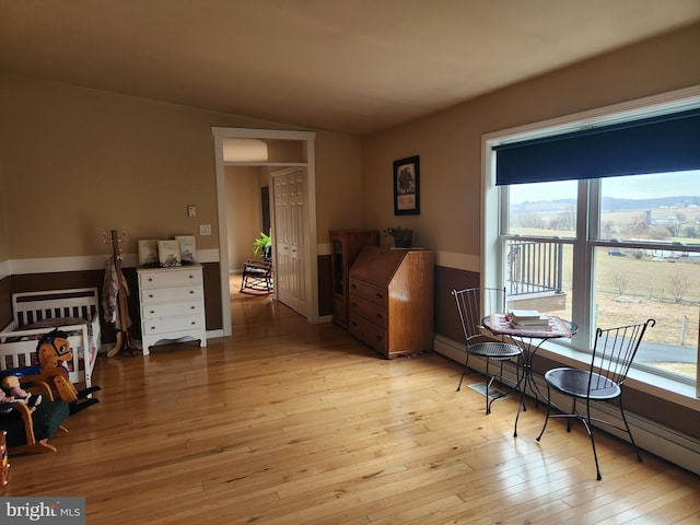 interior space featuring lofted ceiling, light wood-type flooring, and baseboard heating