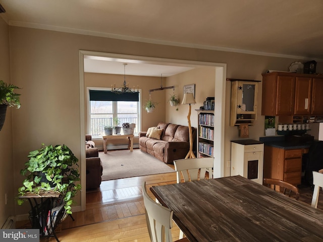 dining room with light wood-style floors, a notable chandelier, and ornamental molding