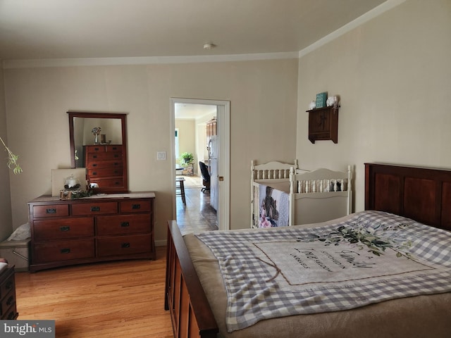 bedroom with crown molding, light wood-style floors, and baseboards