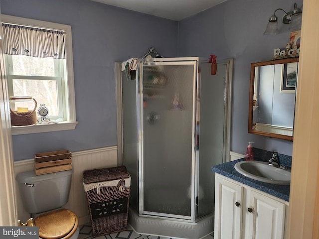 full bathroom with a wainscoted wall, a shower stall, vanity, and toilet