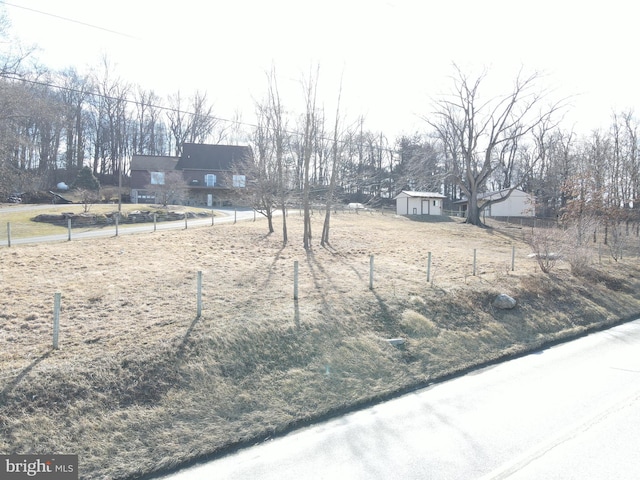 view of yard featuring an outdoor structure, fence, and a shed