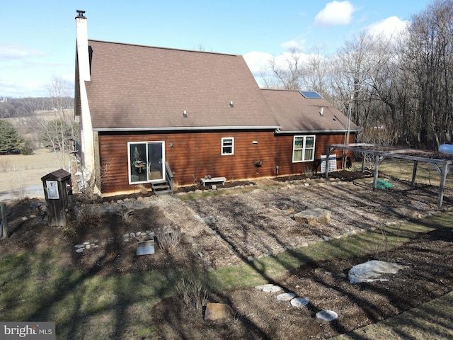 back of property with a chimney and entry steps