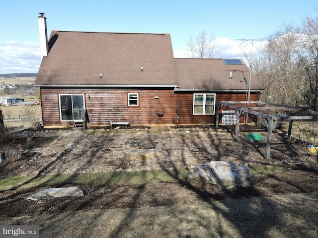 rear view of house featuring fence, roof with shingles, and a chimney