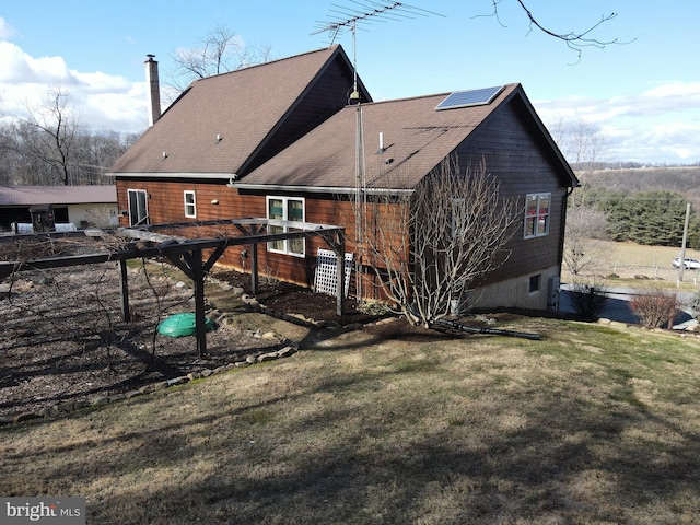 back of property featuring roof mounted solar panels and a lawn