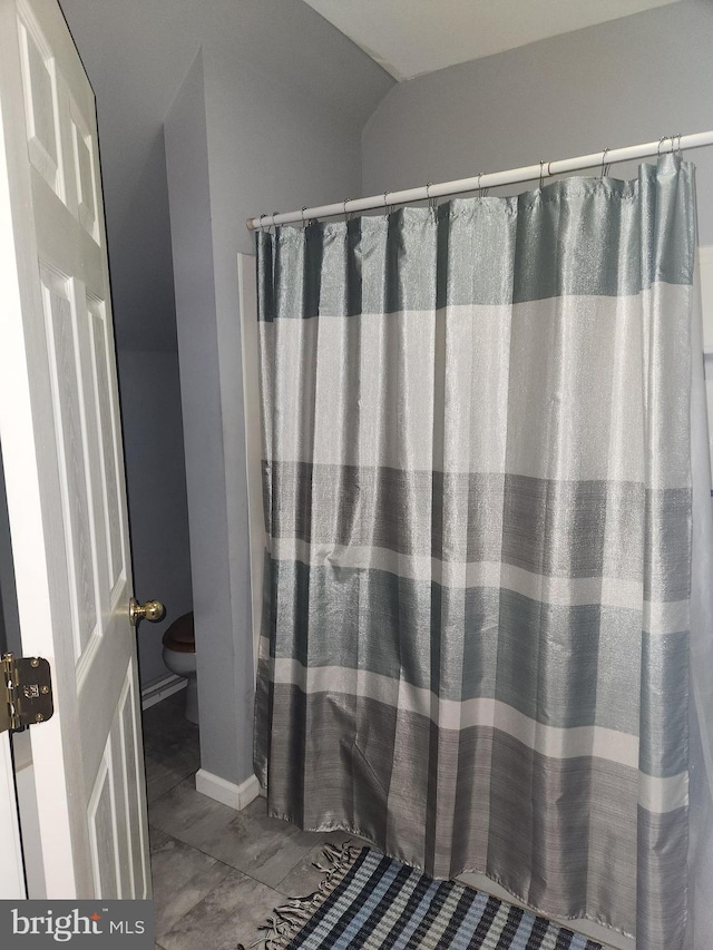 full bath with vaulted ceiling, toilet, and baseboards