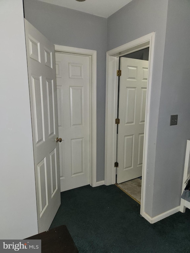 corridor with dark carpet and baseboards