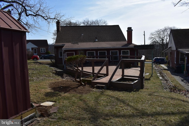 back of house featuring a wooden deck, a lawn, and a chimney