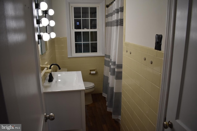 bathroom with toilet, tile walls, wood finished floors, and vanity