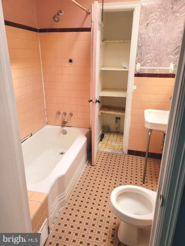 full bathroom with wallpapered walls, tile walls, shower / bathing tub combination, and a wainscoted wall