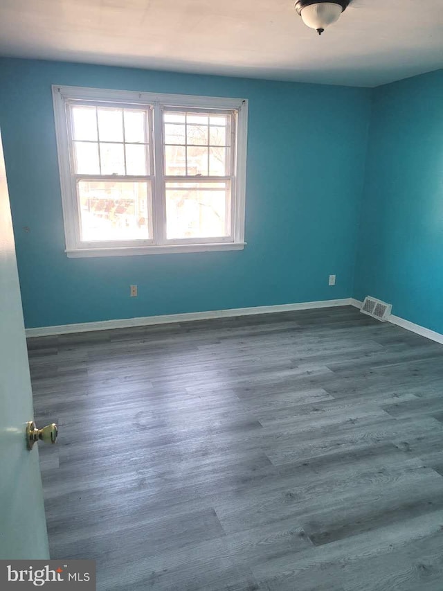 spare room with visible vents, baseboards, and wood finished floors