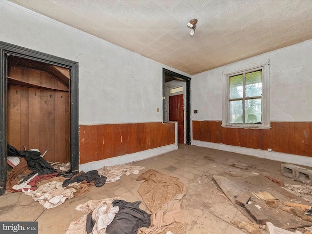 spare room featuring a wainscoted wall and wood walls