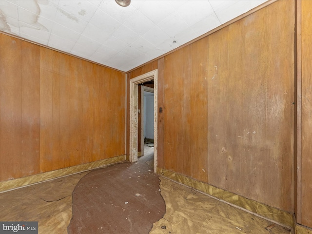 unfurnished room featuring wooden walls