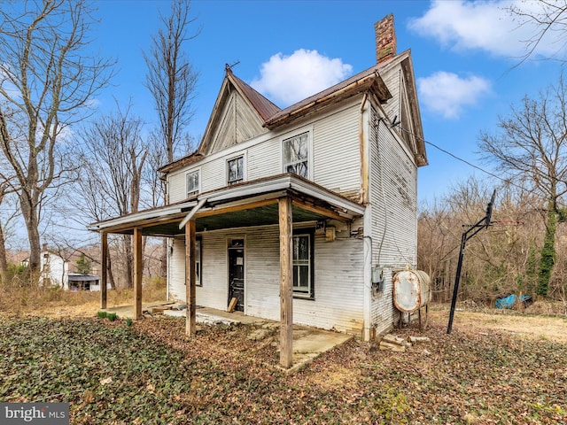 view of front facade with covered porch and a chimney