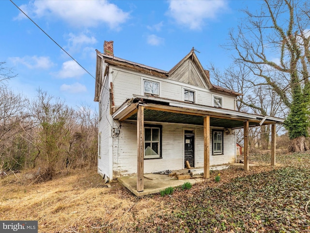 view of front of home with covered porch and a chimney