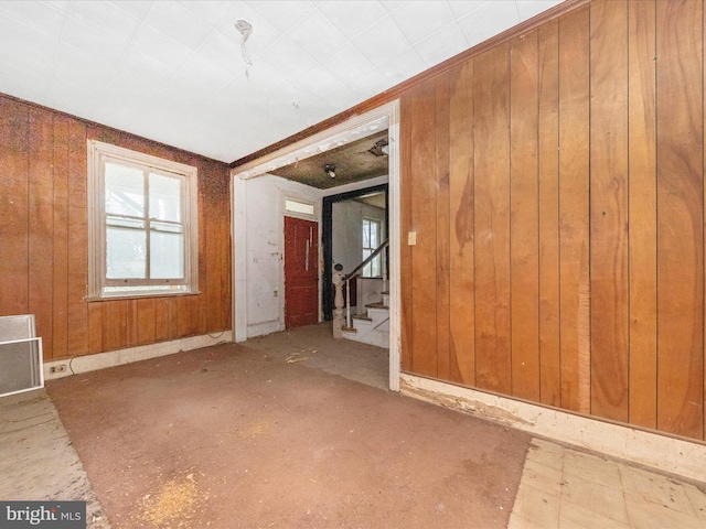 empty room featuring visible vents, wood walls, and stairs