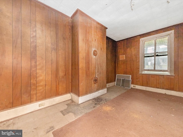 unfurnished room with visible vents, baseboards, and wooden walls