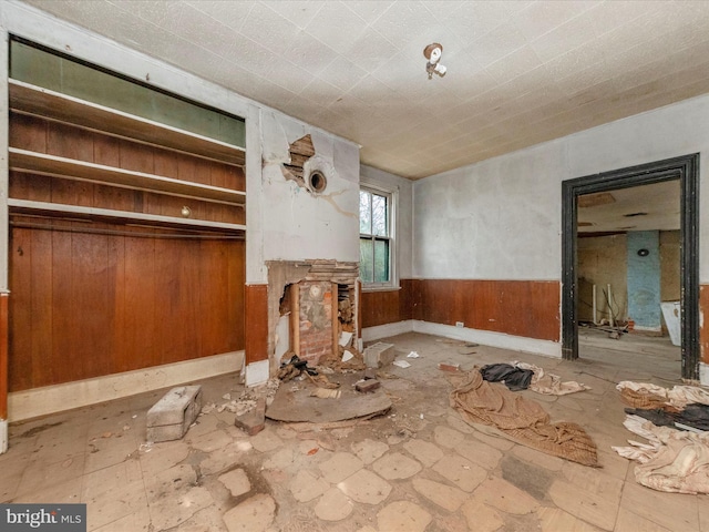 unfurnished living room with a wainscoted wall and wood walls