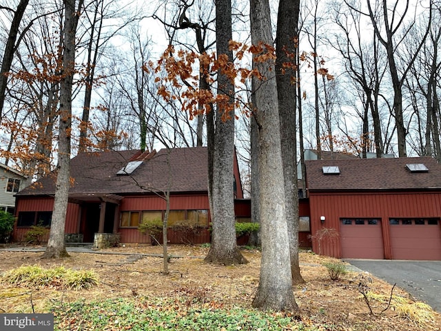 view of front of property with driveway, an attached garage, and roof with shingles