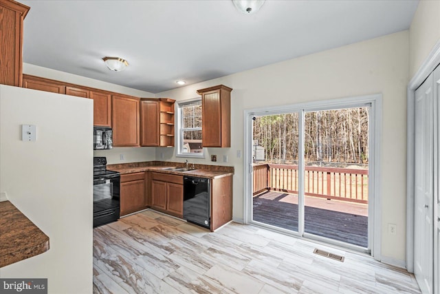 kitchen featuring visible vents, black appliances, a sink, open shelves, and brown cabinetry