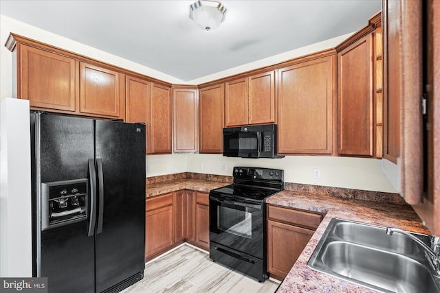 kitchen with a sink, black appliances, and brown cabinetry