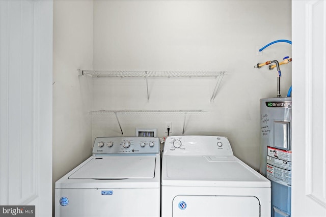 clothes washing area with separate washer and dryer, water heater, and laundry area