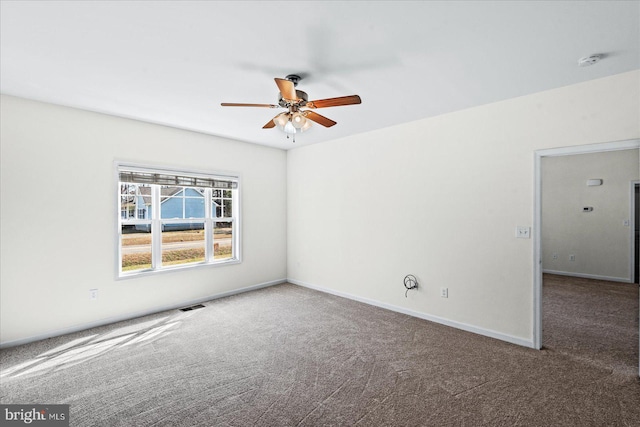 carpeted spare room with a ceiling fan, visible vents, and baseboards