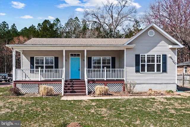 view of front facade with fence, covered porch, a front lawn, and a shingled roof