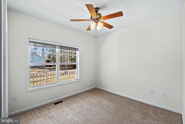 carpeted empty room featuring visible vents, a ceiling fan, and baseboards