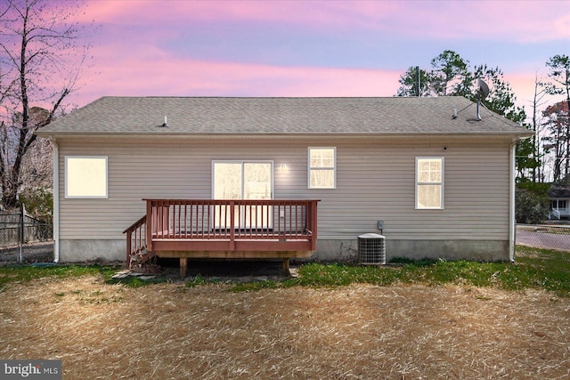 rear view of property with a shingled roof, central AC, a deck, and fence