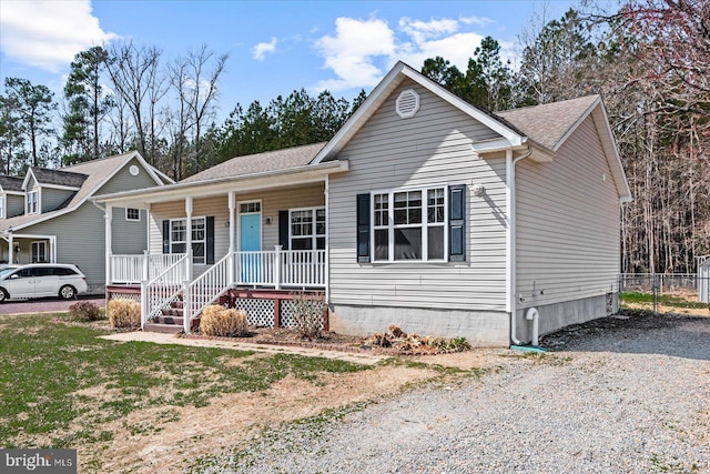 view of front of house featuring gravel driveway, a porch, fence, and roof with shingles