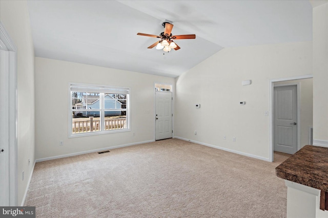 unfurnished living room with a ceiling fan, visible vents, baseboards, vaulted ceiling, and carpet flooring