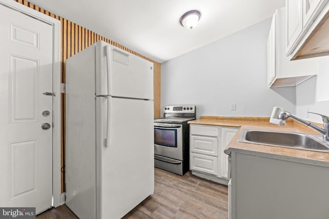 kitchen with white cabinets, a sink, stainless steel electric range, freestanding refrigerator, and light countertops